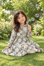 Load image into Gallery viewer, Girl sitting on the grass in the all-over Sage Floral dress with her hood down