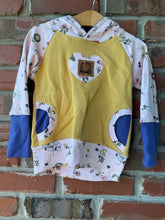 Load image into Gallery viewer, Honey-yellow hoodie with bee-and-flower print sleeves and hood, blue cuffs, front pockets, and heart applique.

